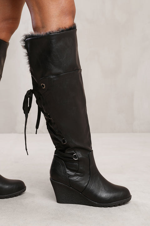 BRIDGET WEDGE HEEL MID CALF HIGH BOOTS WITH FUR & LACE UP DETAIL IN BLACK FAUX LEATHER